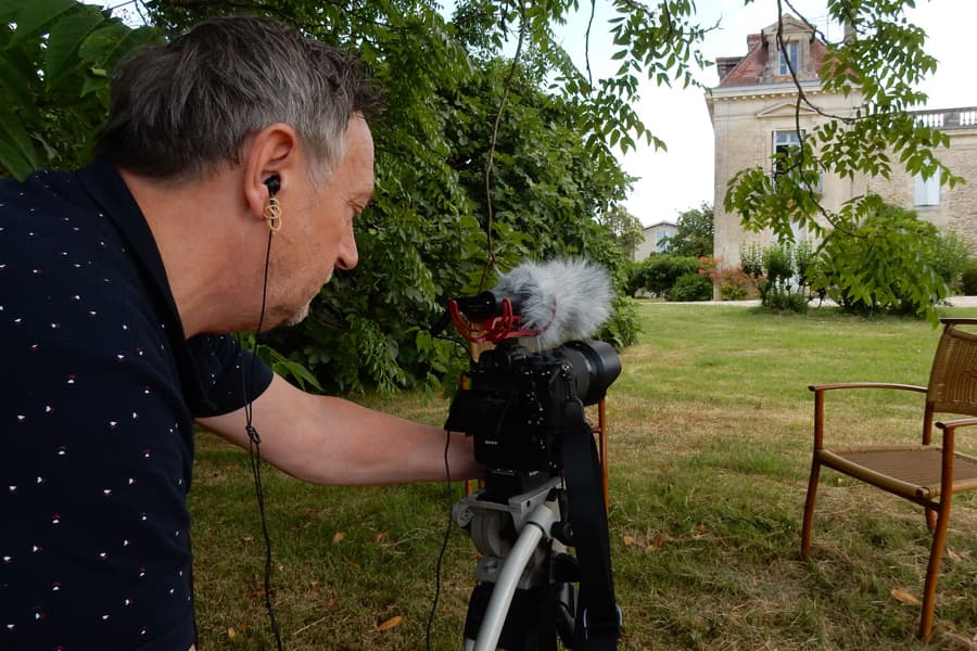 Thierry Bonnaffé filmt in een tuin, met de camera op statief